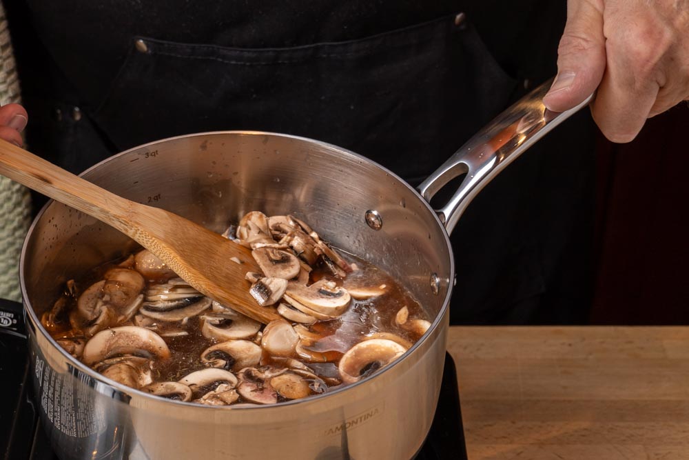 Mushrooms cooking in beef broth for a French dip cheeseburger