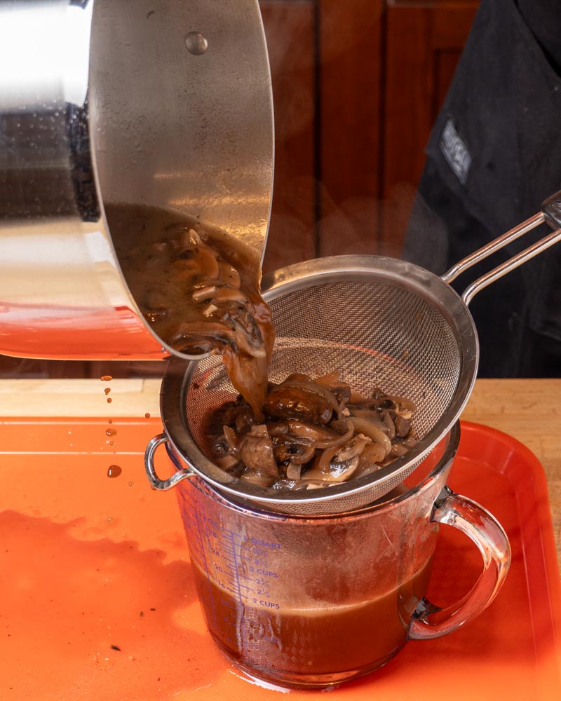 Straining beef broth through a strainer